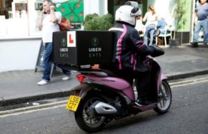 An UberEATS food delivery courier rides her scooter in London